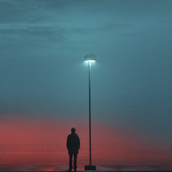 Person standing at the edge of a path, looking ahead with a small light or lantern