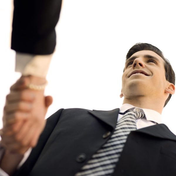 Atractive businessman and businesswoman shaking hands outside of office building. Couple working.