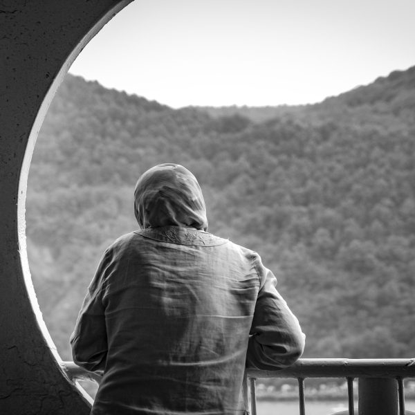 A female wearing a hijab standing on a balcony in black and white