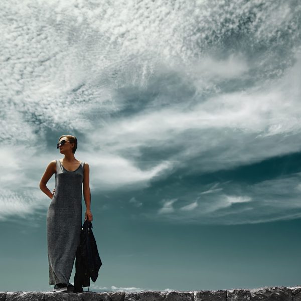 stylish girl woman in casual hipster clothes posing behind sky with clouds