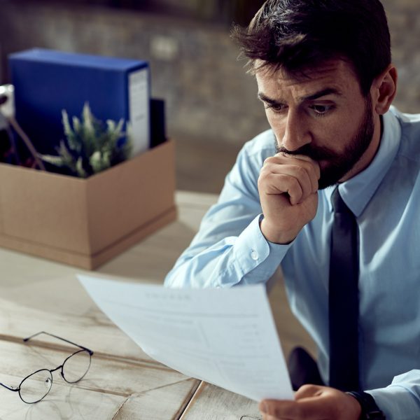 Worried businessman going through paperwork after losing his job in the office.